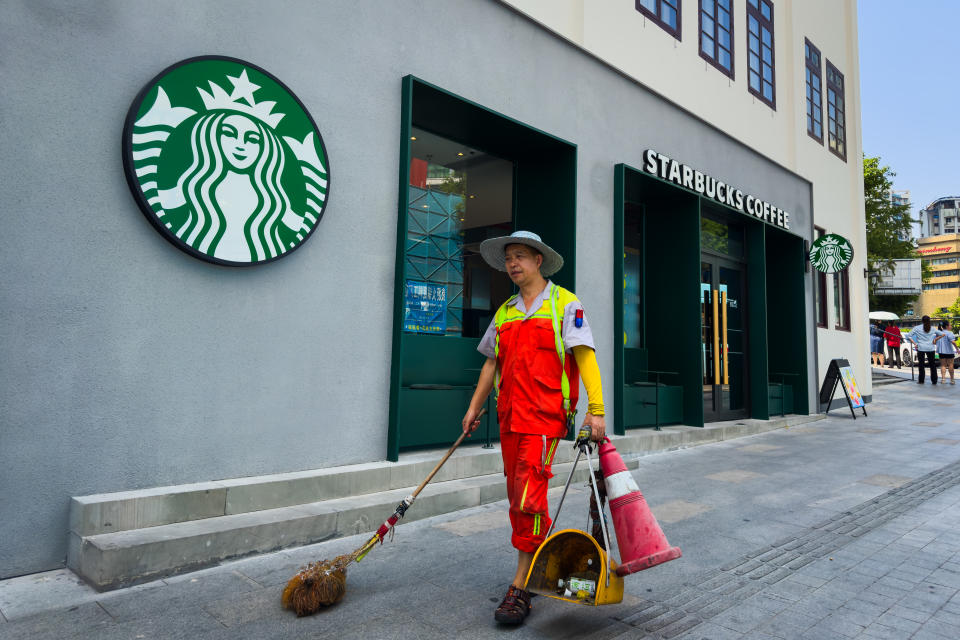 CHONGQING, CHINA - SEPTEMBER 10: A street cleaner walks past a Starbucks Coffee store with cleaning tools on September 10, 2024 in Chongqing, China. (Photo by Cheng Xin/Getty Images)