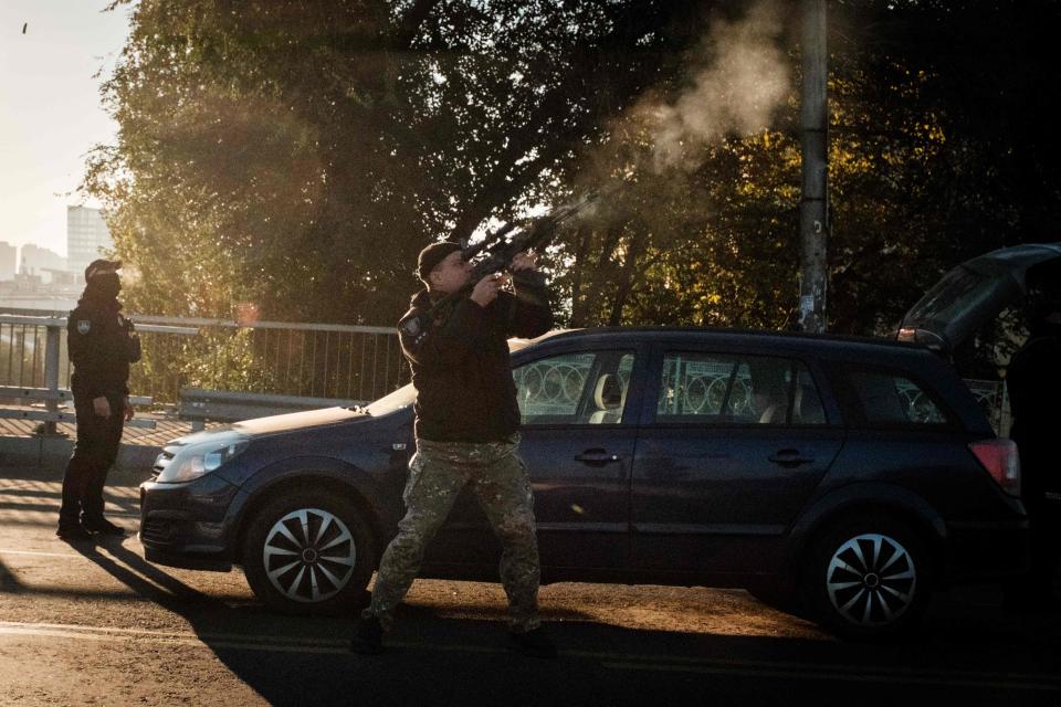 A police officer fires at a flying drone following attacks in Kyiv on October 17, 2022, amid the Russian invasion of Ukraine.