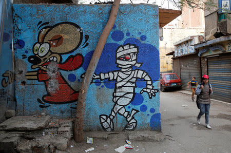 Children walk past a graffiti painted on the wall of a building located inside the 15th-century complex built by Mameluk Sultan al-Ashraf Qaitbey, in Cairo's City of the Dead, Egypt February 13, 2017. REUTERS/Amr Abdallah Dalsh