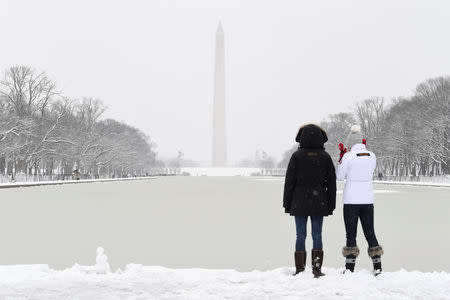 Visitors bundle up against the snow and freezing temperatures left by Winter Storm Gia, which paralyzed much of the nation's midsection, at the Reflecting Pool with the Washington Monument in the background, in Washington, D.C., U.S., January 13, 2019. REUTERS/Mike Theiler