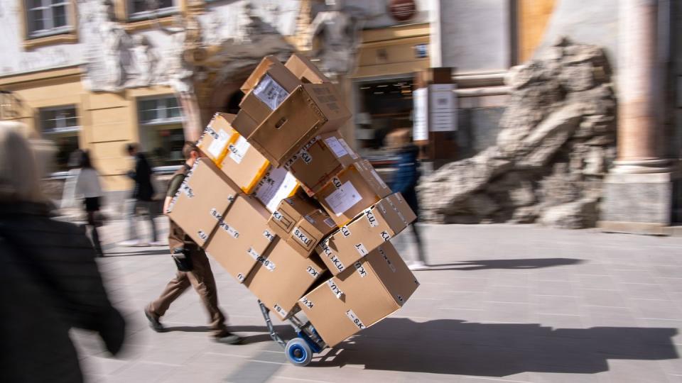 Ein Paketzulieferer transportiert mit einer Sackkarre mehrere Pakete durch die Münchener Innenstadt.