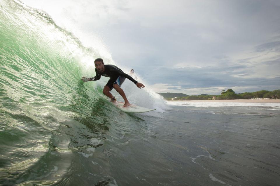 A man surfing down a barrel wave in Playa De Colorado, Nicaragua