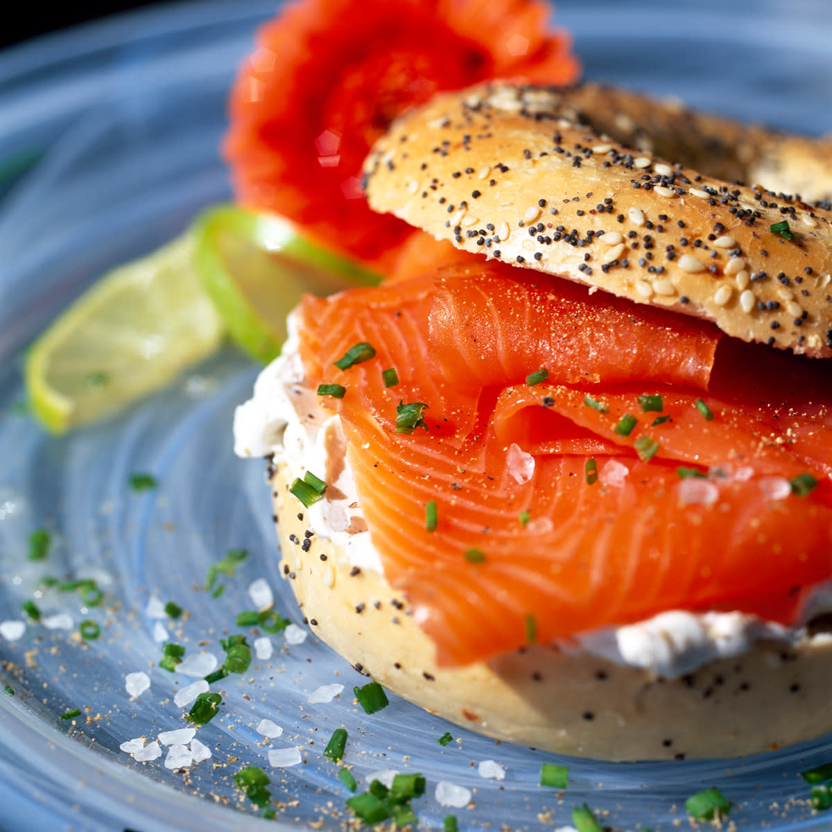 Smoke salmon on an everything bagel sits on a blue plate. 