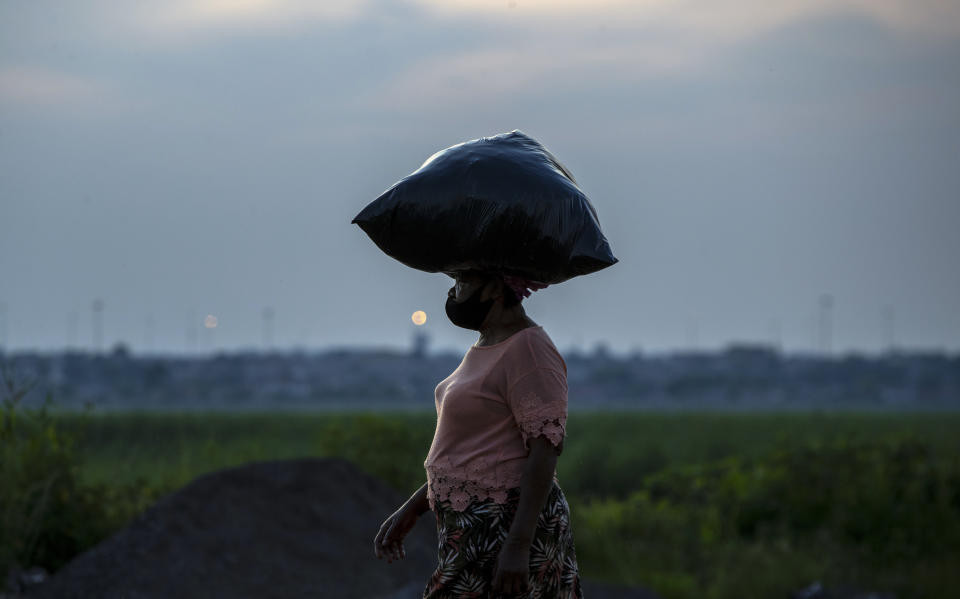 A woman wearing a face mask as a precaution against coronavirus outbreak walk back home from work in Spruitview near Johannesburg, South Africa, Friday, Jan. 8, 2021. (AP Photo/Themba Hadebe)