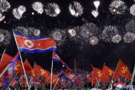 People wave North Korean flags beneathe a fireworks display during commemorations of the 75th anniversary of the founding of the ruling Workers' Party of Korea (WPK), in Pyongyang