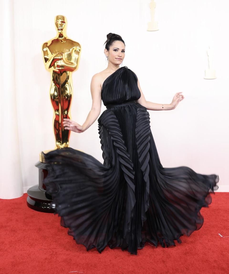 Tiffany Smith wears a voluminous pleated black gown.