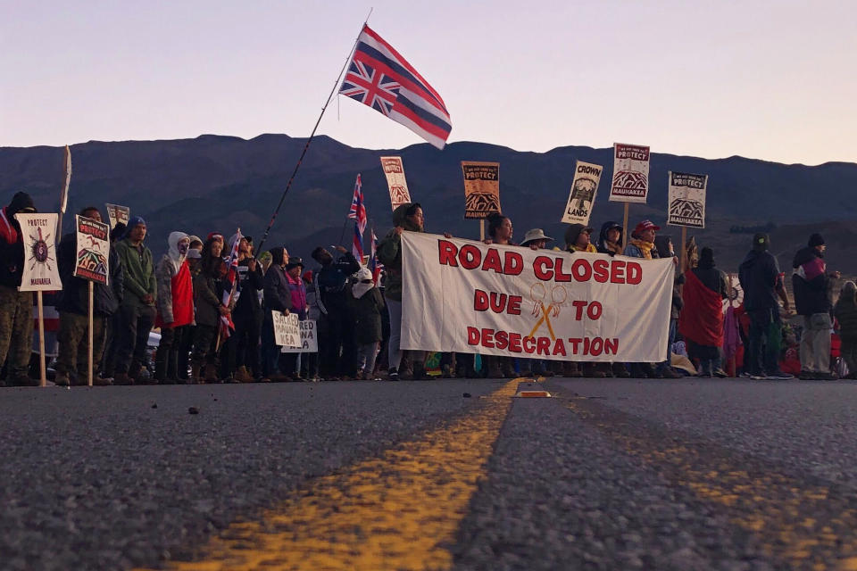 Demonstrators are gather to block a road at the base of Hawaii's tallest mountain, Monday, July 15, 2019, in Mauna Kea, Hawaii, to protest the construction of a giant telescope on land that some Native Hawaiians consider sacred. (AP Photo/Caleb Jones)