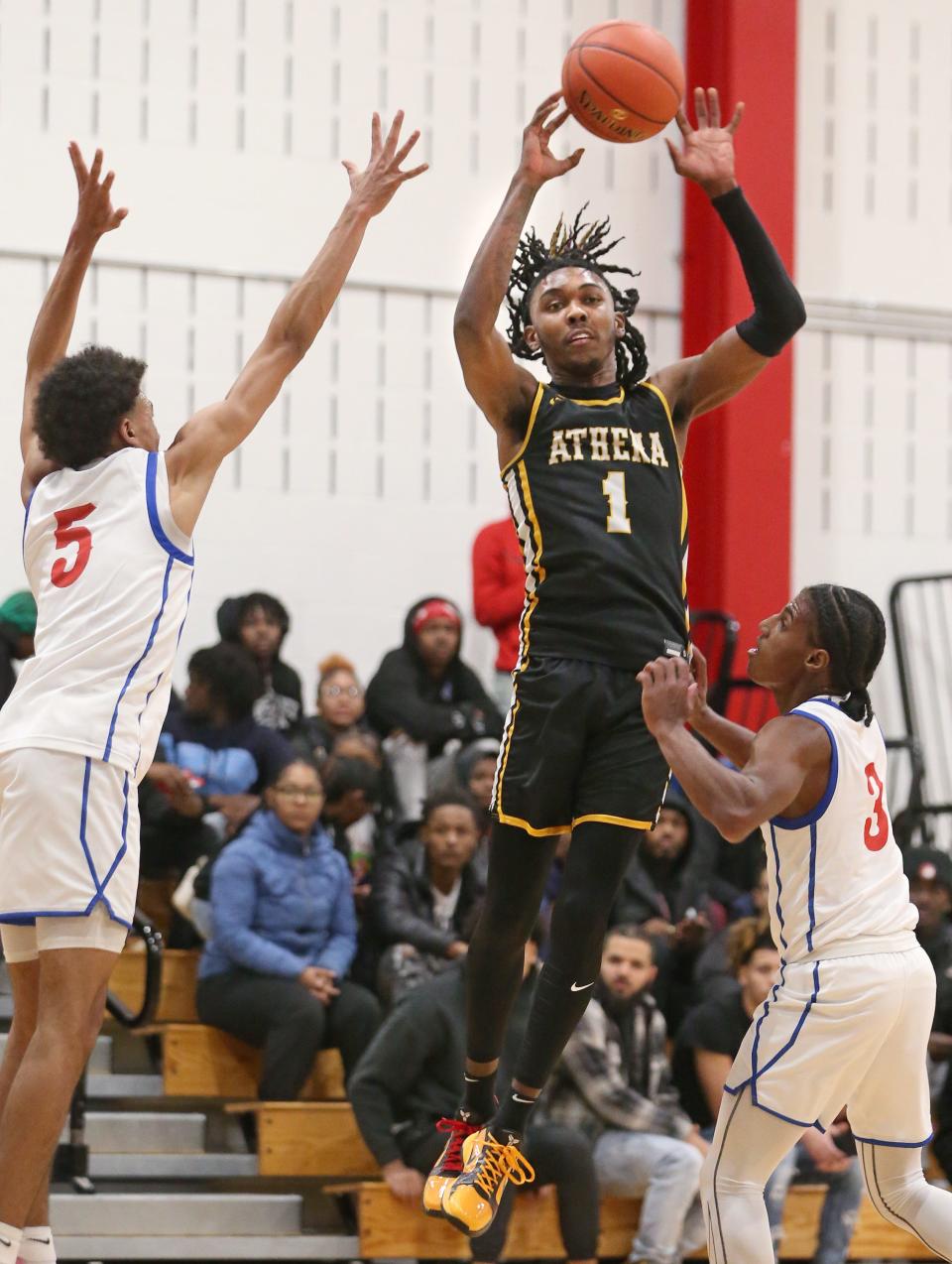 Greece Athena senior guard Khorie Reaves draws two Monroe defenders, Marcus Freeman and William McKinney, before throwing a cross court pass to the deep corner where teammate Zacarr Johnson then hit an open three point shot in the first quarter during their Section V boys basketball game Monday, Dec. 18, 2023 at James Monroe High School in Rochester.