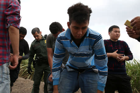 Border patrol agent Robert Rodriguez apprehends immigrants who illegally crossed the border from Mexico into the U.S. in the Rio Grande Valley sector, near McAllen, Texas, U.S., April 3, 2018. REUTERS/Loren Elliott