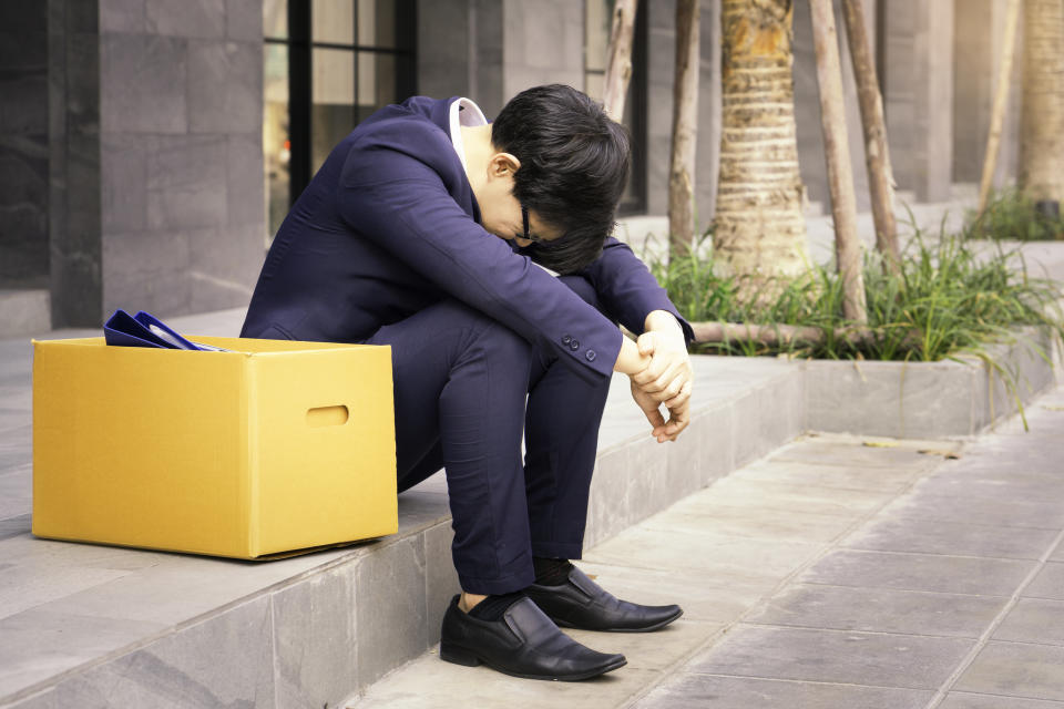 Businessman sitting hopelessly on stair in central business district due to unemployment. 