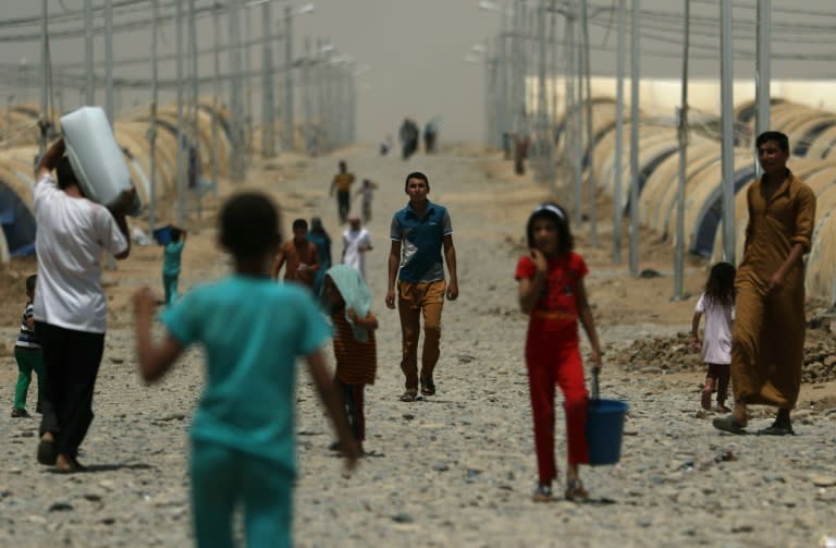 Iraqis who fled the violence around the northern city of Mosul walk at the Jadaah camp on July 19, 2017