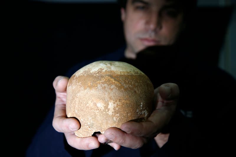 Dr. Omri Barzilai from the Israel Antiquities Authority displays a partial skull retrieved from a cave in northern Israel, in Jerusalem