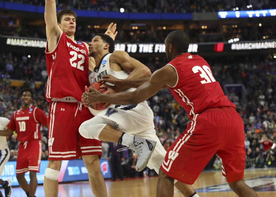Villanova guard Josh Hart, center, drives to the basket against Wisconsin forward Ethan Happ, left, and forward Vitto Brown, right, with three seconds remaining in the second half of a second-round men's college basketball game in the NCAA Tournament, Saturday, March 18, 2017, in Buffalo, N.Y. (AP Photo/Bill Wippert)