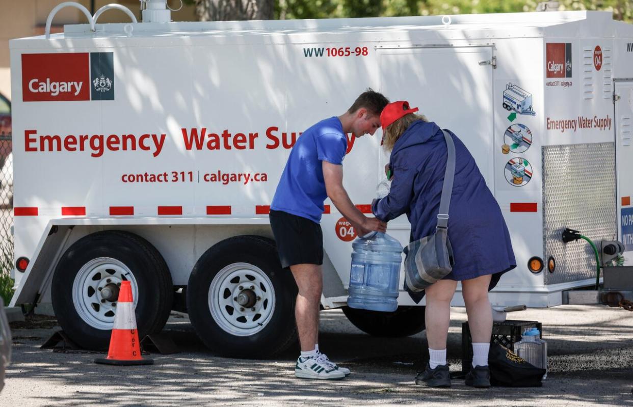 Ian Dyer fills a water jug with help from a friend at an emergency supply provided by the city as work to repair a major water main stretches into a second day in Calgary, Friday, June 7, 2024. (Jeff McIntosh/The Canadian Press - image credit)