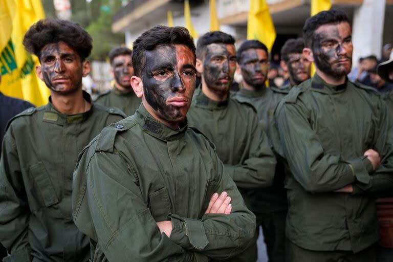 Combatientes de Hezbollah asisten a una procesión fúnebre de dos de sus compañeros que murieron por artillería israelí, el martes 10 de octubre de 2023, en el poblado de Khirbet Selm, en el sur de Líbano.  (AP Foto/Hussein Malla)