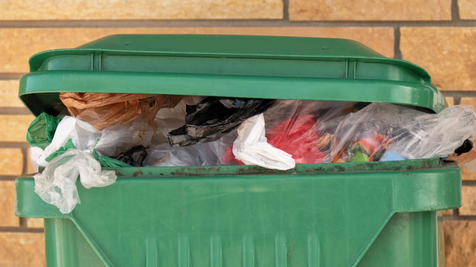 A trash can with trash flowing out of the top