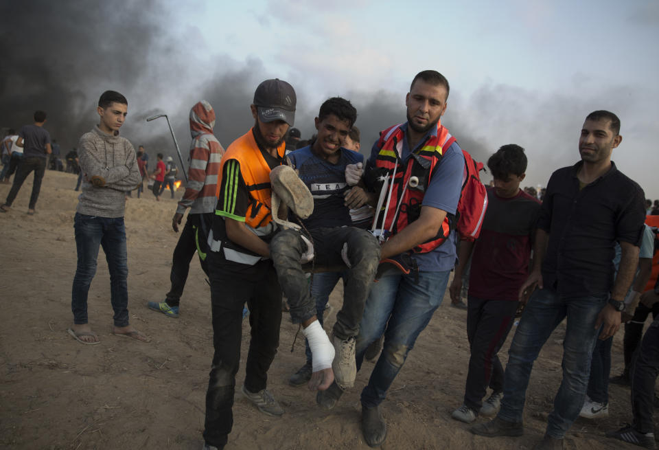 Palestinian medics evacuate a wounded protester at the Gaza Strip's border with Israel, Friday, Oct. 19, 2018. (AP Photo/Khalil Hamra)