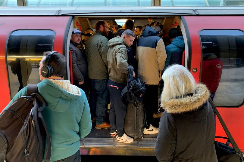 Passengers squeeze on to a busy Central line underground train at Stratford station