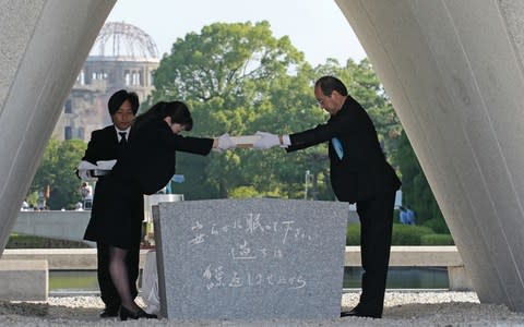 Hiroshima Mayor Kazumi Matsui (R) offers a new list of A-bomb dead, including individuals who died since last year's anniversary from the side effects of radiation - Credit: AFP