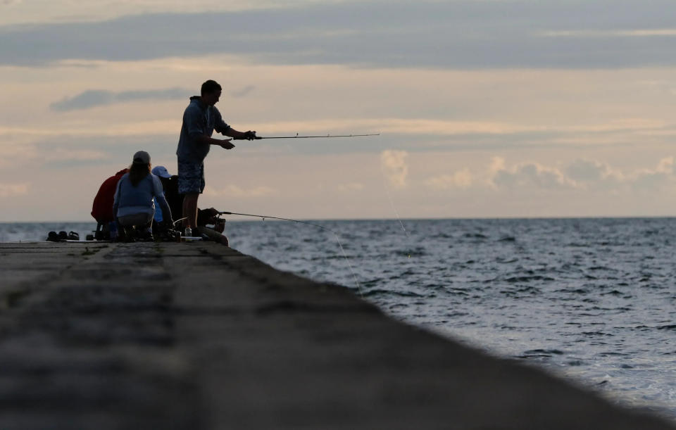 People fish off the breakwater barrier at Stearns Park Beach in Ludington, Michigan, June 23, 2017.