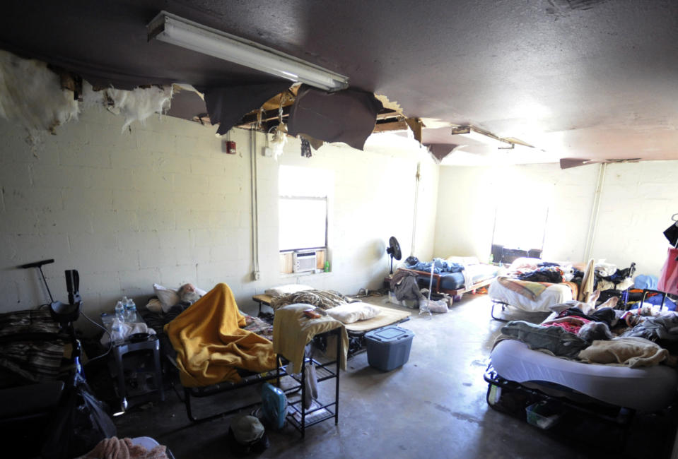 Homeless men rest on cots in a storm-damaged dormitory at Bread of Life Mission Inc., in Punta Gorda, Fla., on Saturday, Oct. 8, 2022. A few miles meant the difference between life and death when Hurricane Ian struck, and contrasting scenes of recovery and destruction show how a disaster can mean different things to different people. (AP Photo/Jay Reeves)