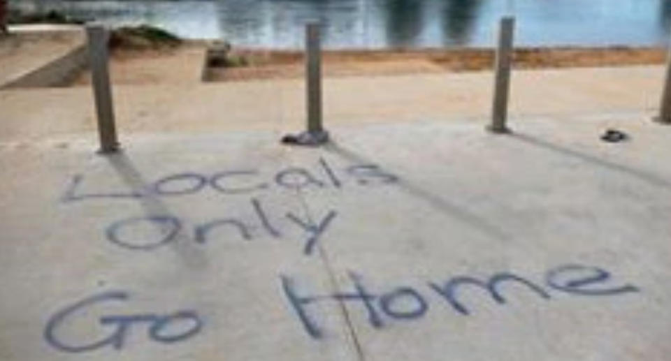 The words 'Locals only Go home' have been spray painted onto a sidewalk. 
