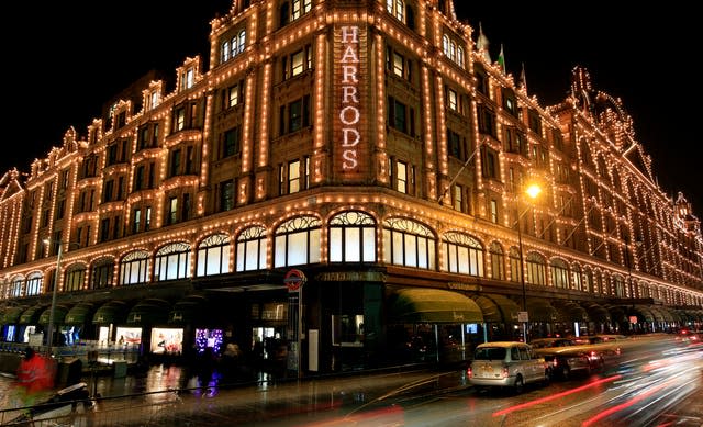 Harrods department store lit up at night with cars driving past