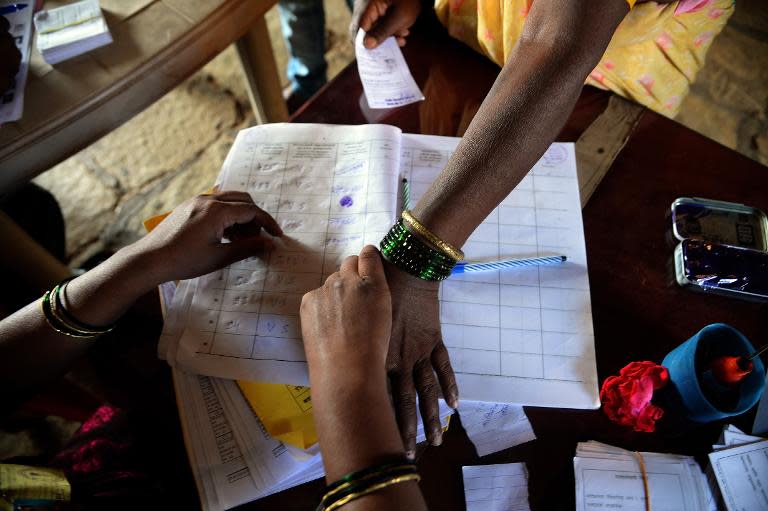 An Indian election official takes a thumb-print from an illiterate voter at a polling station in the Shirgaon village of Pune district, some 130 kms south-east of Mumbai, on April 17, 2014