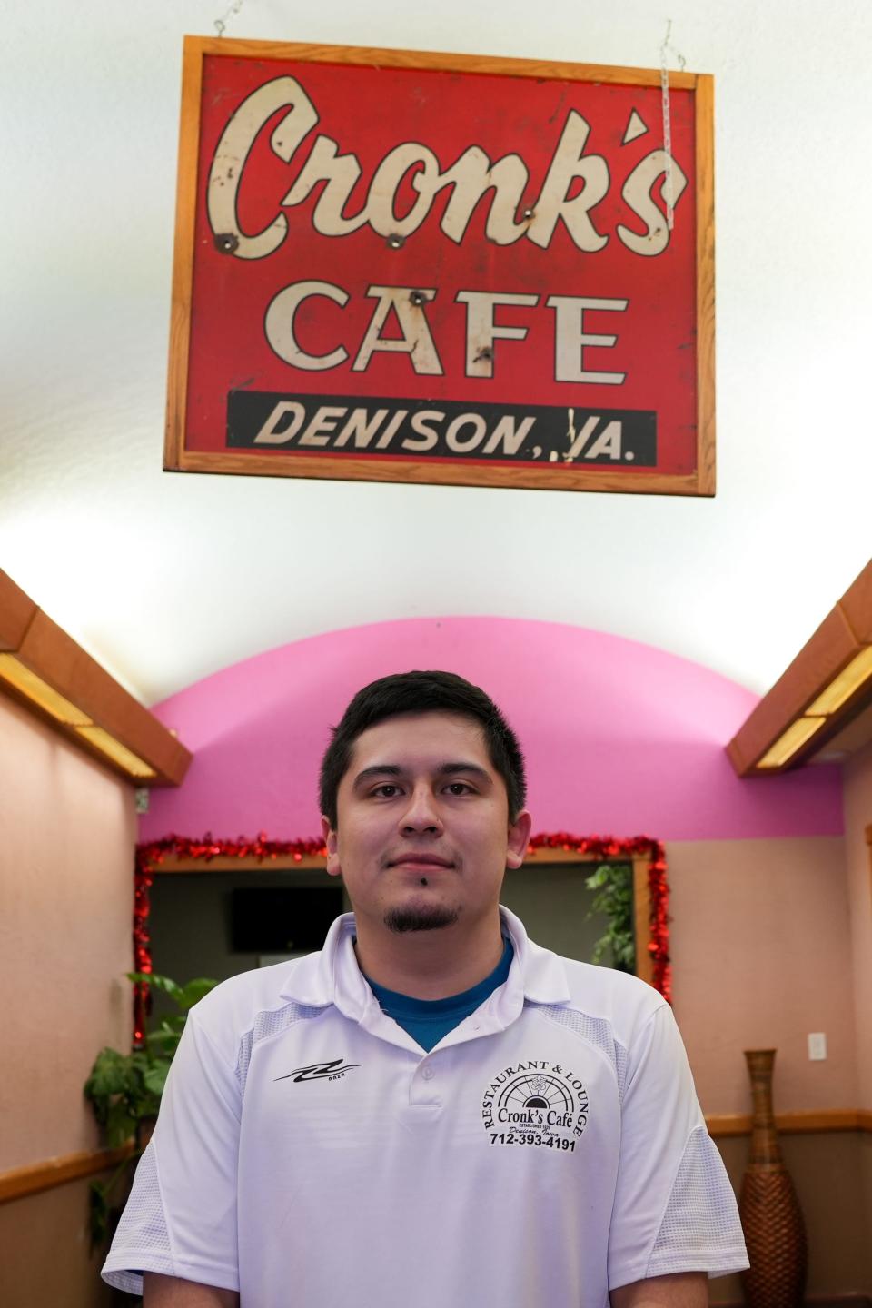 Omar Patino, co-owner of Cronk's Café, poses for a photo with one of Cronk's old signs.