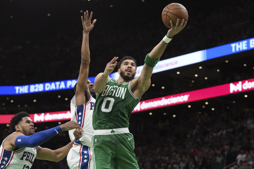 Boston Celtics forward Jayson Tatum (0) shoots at the basket as Philadelphia 76ers forward Tobias Harris, left, and guard De'Anthony Melton, behind center, defend during the second half of Game 7 in the NBA basketball Eastern Conference semifinal playoff series, Sunday, May 14, 2023, in Boston. (AP Photo/Steven Senne)