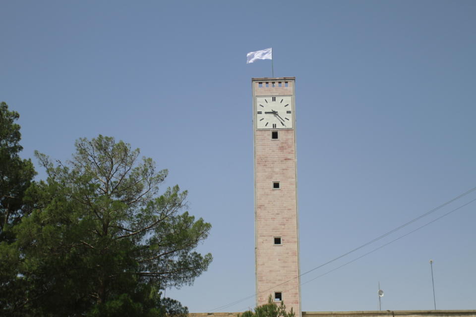 A Taliban flag flies from the clocktower of the Herat provincial official office, in Herat, Afghanistan, west of Kabul, on Saturday, Aug. 14, 2021. (AP Photo/Hamed Sarfarazi)