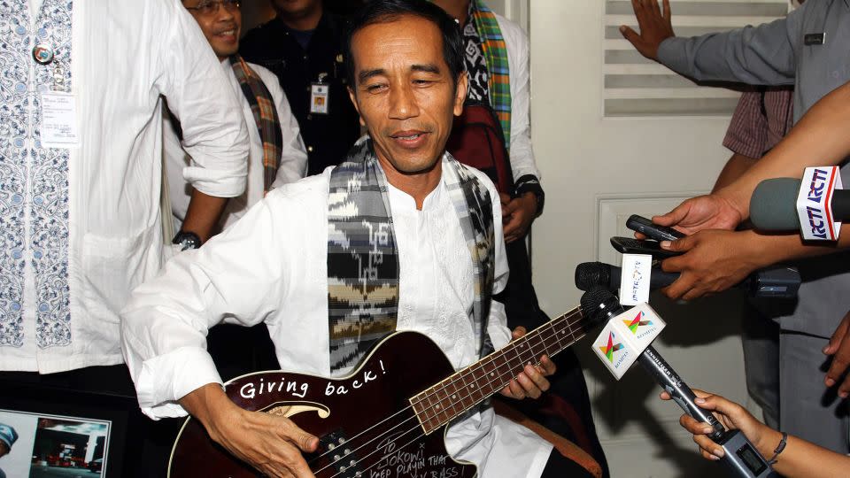 This picture taken in 2013 shows then-Jakarta governor Jokowi holding an autographed maroon bass guitar gifted to him by Metallica's Robert Trujillo. - AFP/Getty Images