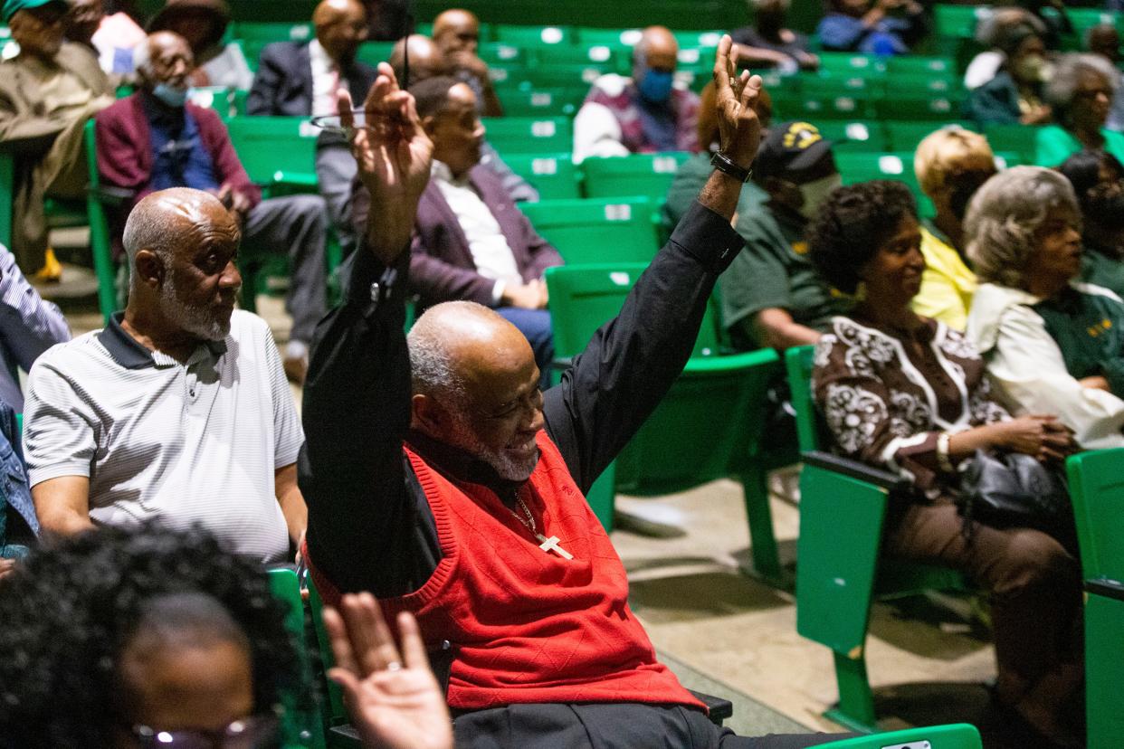Michael Love raise his hands as he and other audience members raise their hands if they are alumni of Booker T. Washington High School during the Nat D. Williams street naming ceremony in the school’s auditorium in Memphis, Tenn., on Friday, October 27, 2023. Williams, who was hailed as the first Black radio personality in Memphis and “The Voice of Beale Street,” was a history teacher at the school for 43 years. Love was one of Williams’ students and lived in his neighborhood and at times would be driven to school by Williams. “It means that a great man is finally getting his due and his memory will live on,” Love said on the sign being put up.