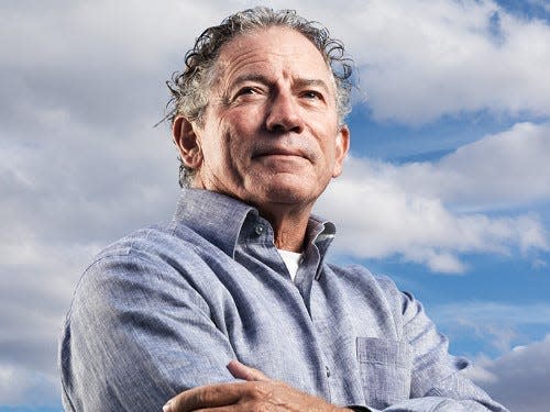 A headshot of Thomas Siebel standing in front of a cloudy backdrop