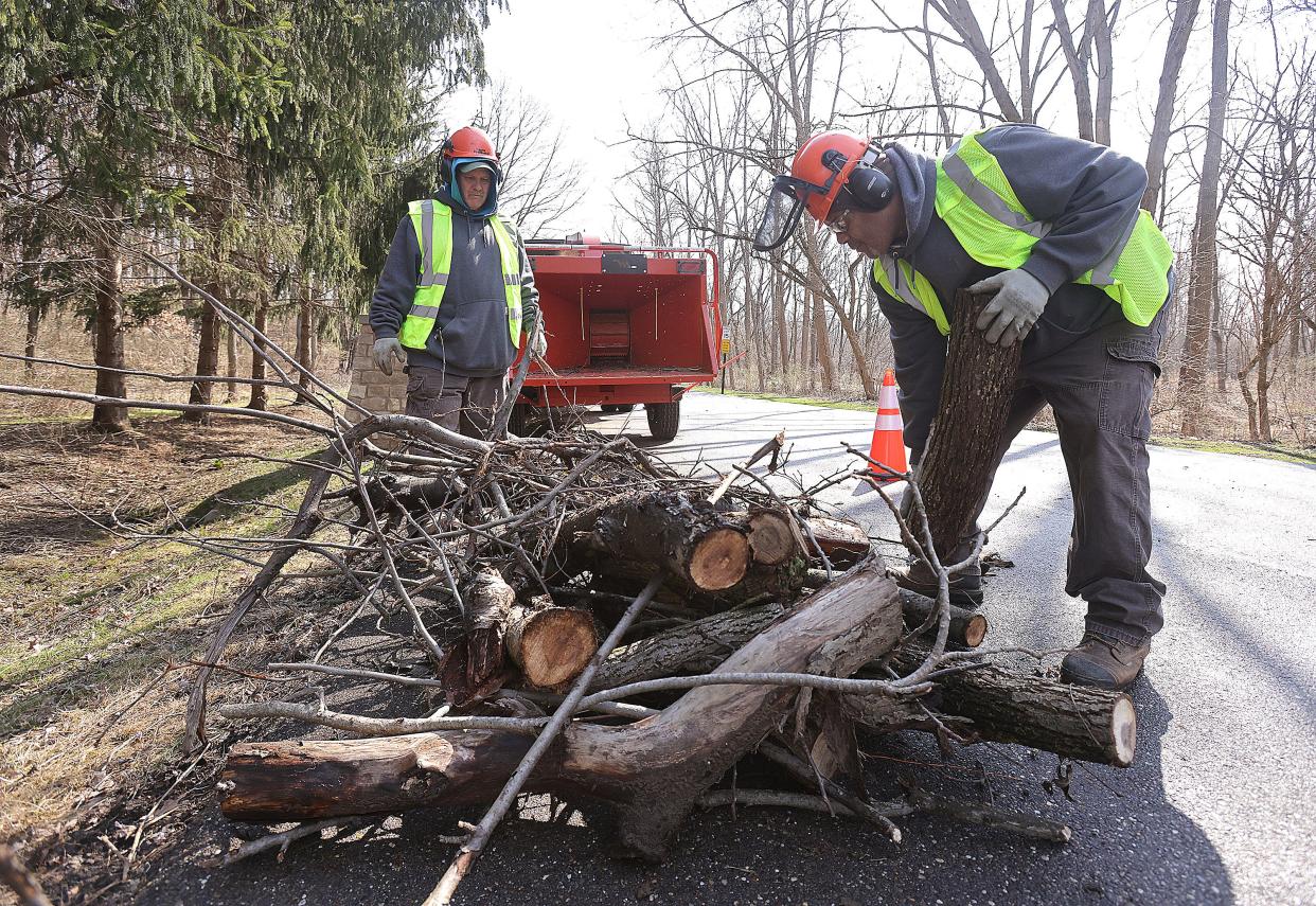 Stark Parks employees Burt Frenz, left, and Larry Bell work to chip wood during a cleanup of the entrance to the Wildlife Conservation Center in Perry Township.