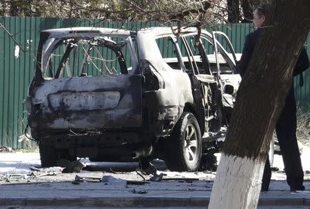 A man stands next to the wreckage of a car destroyed in an explosion, during which Ukrainian state security service (SBU) officer Lieutenant Colonel Oleksandr Kharaberiush was killed, in the eastern port city of Mariupol, Ukraine March 31, 2017. REUTERS/Nikolai Ryabchenko