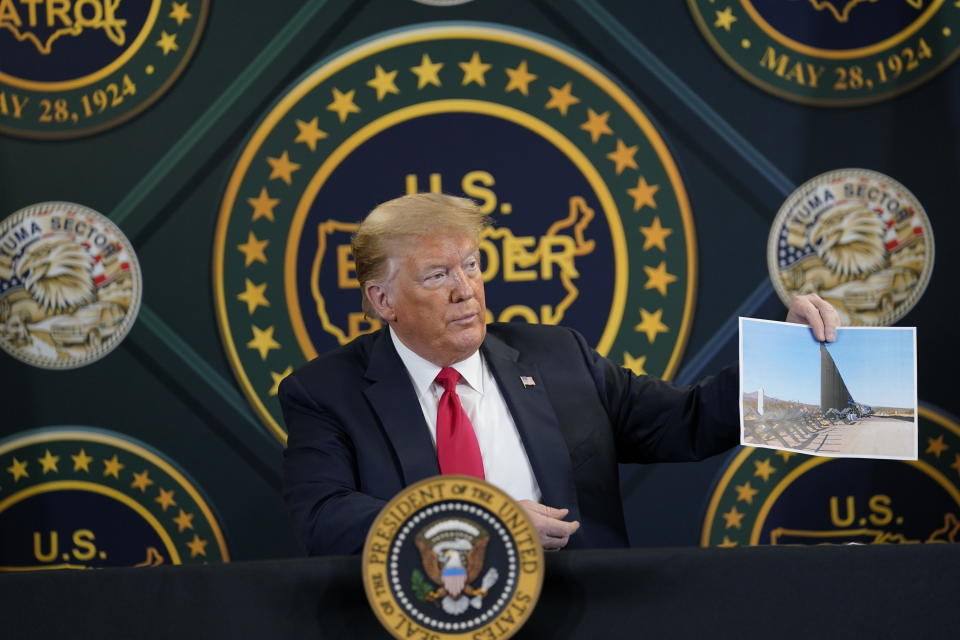 El presidente estadounidense Donald Trump muestra una foto del muro que se está construyendo en la frontera con México, en la Estación de la Patrulla Fronteriza en Yuma, el martes, 23 de junio del 2020. (AP Foto/Evan Vucci)