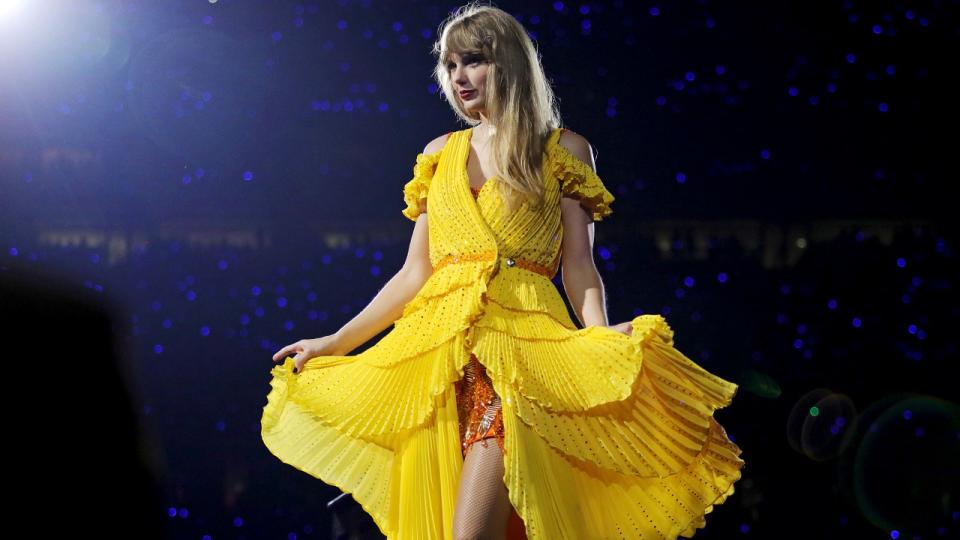 Taylor Swift showing off her yellow duster on the Eras Tour.