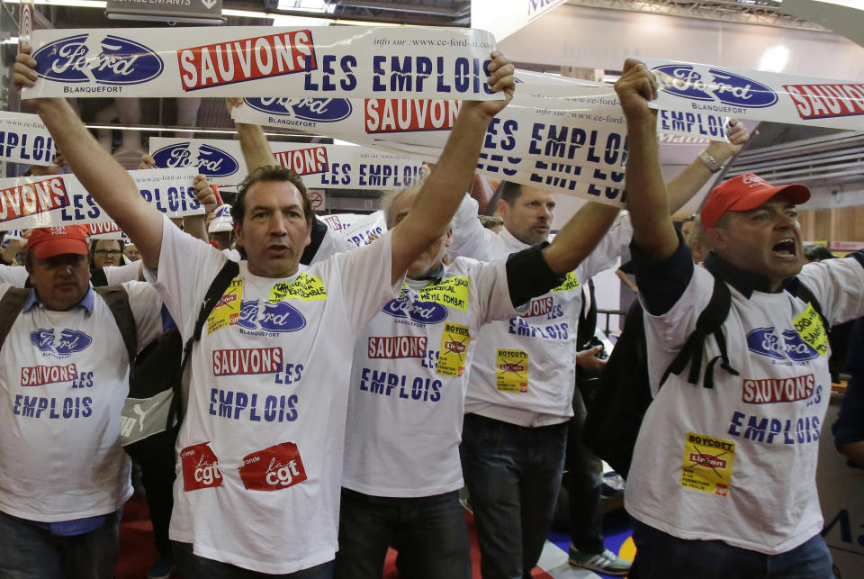 Workers from a Ford factory in France, holding giant stickers that read: "Save the Jobs", protest against factory policy as they march through the Paris Auto Show, France, Saturday, Sept. 29, 2012. The workers swarmed the Paris Auto Show with giant stickers, plastering about 20 cars around the hall to protest lost jobs in the automotive industry. (AP Photo/Michel Euler)