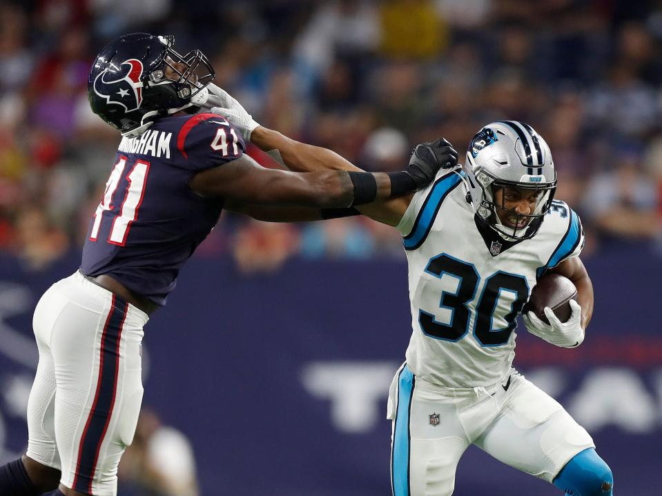 Chuba Hubbard stiff-arms a defender.