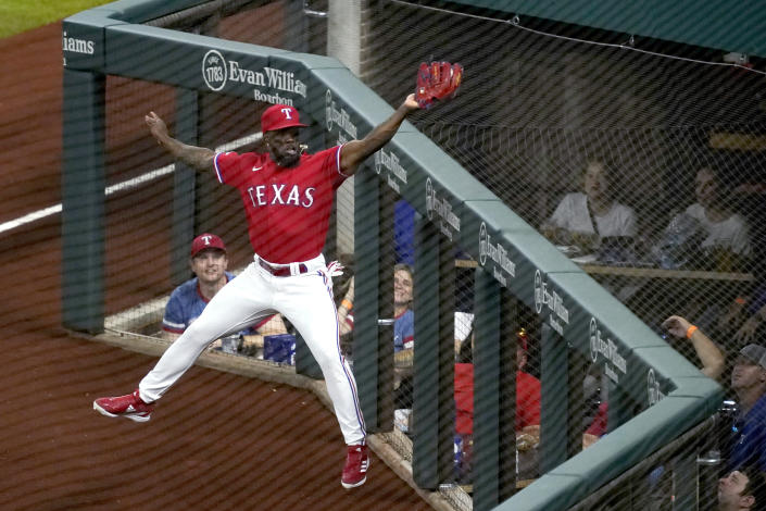 Texas Rangers right fielder Adolis Garcia leaps to catch a fly ball by Seattle Mariners' Eugenio Suarez in foul territory during the first inning of a baseball game Friday, July 15, 2022, in Arlington, Texas. (AP Photo/Tony Gutierrez)