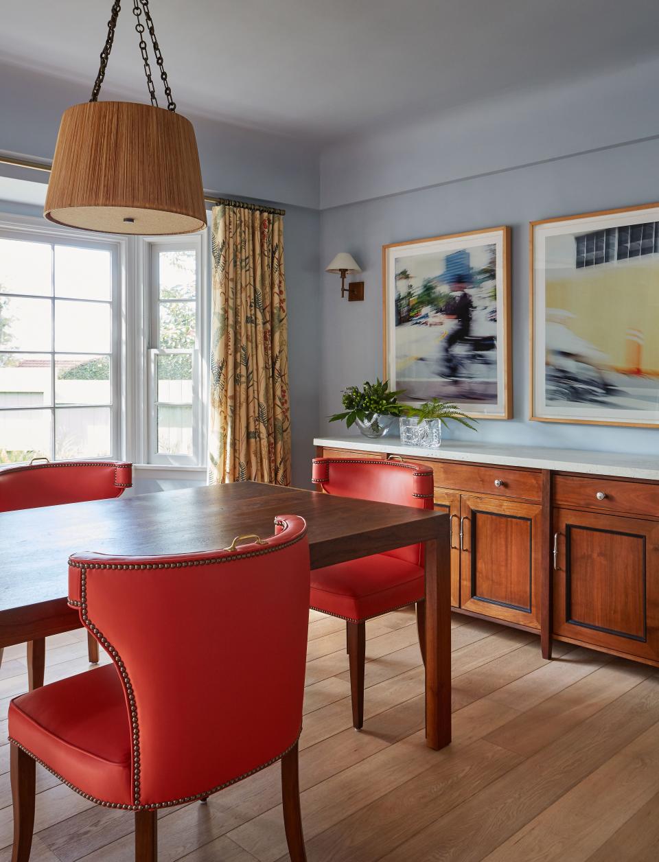 Inspired by Diana Vreeland’s New York City apartment, Martel wanted something bright, but she wasn’t sure where. Martin & Brockett designer Jason Martin convinced her to use a fiery orange shade on grommeted dining chairs that he designed (and fittingly named The Hale). A Broad Beach raffia pendant hangs above the table, also by Martin & Brockett. Jen Mayo, a production coordinator on Arrested Development, photographed the artwork above the buffet.