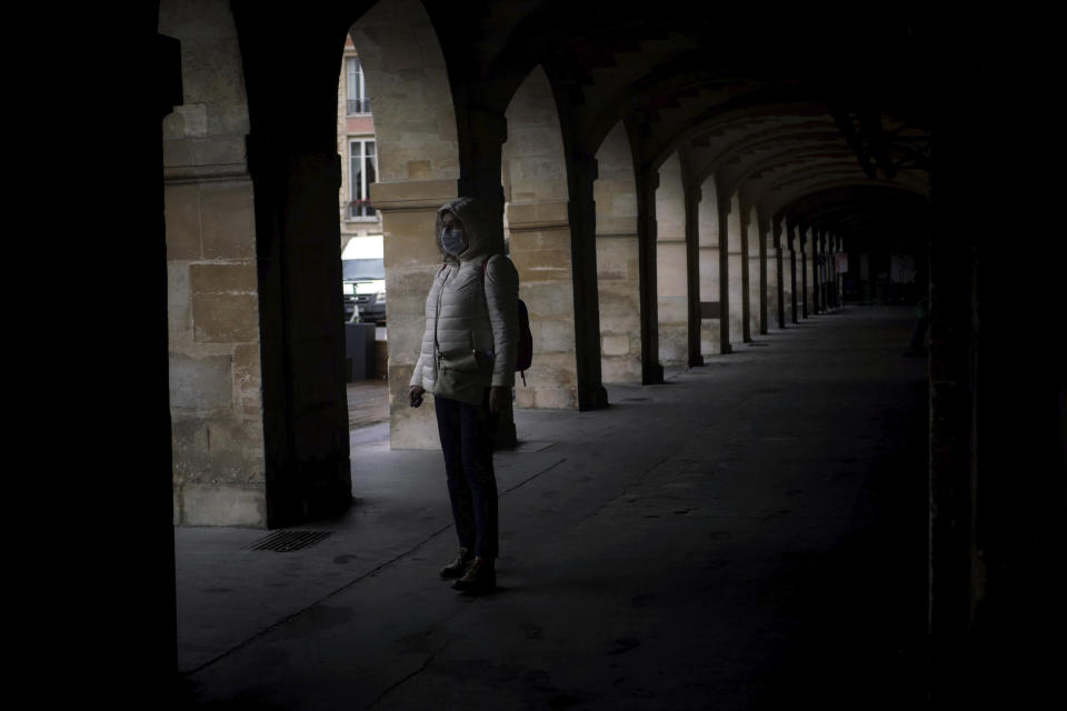 A woman wears a mask as she walks in a street of Paris, Tuesday, Oct. 27, 2020. France's government is holding emergency virus control meetings Tuesday and warning of possible new lockdowns, as hospitals fill up with new COVID patients and doctors plead for backup. (AP Photo/Thibault Camus)