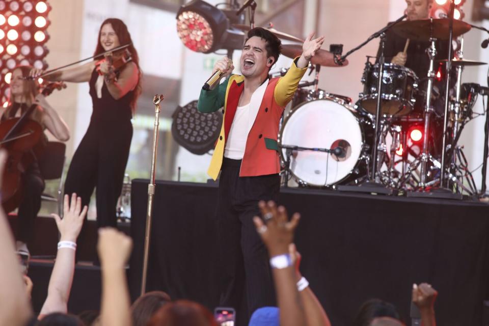 A man in a colorful blazer singing on a stage