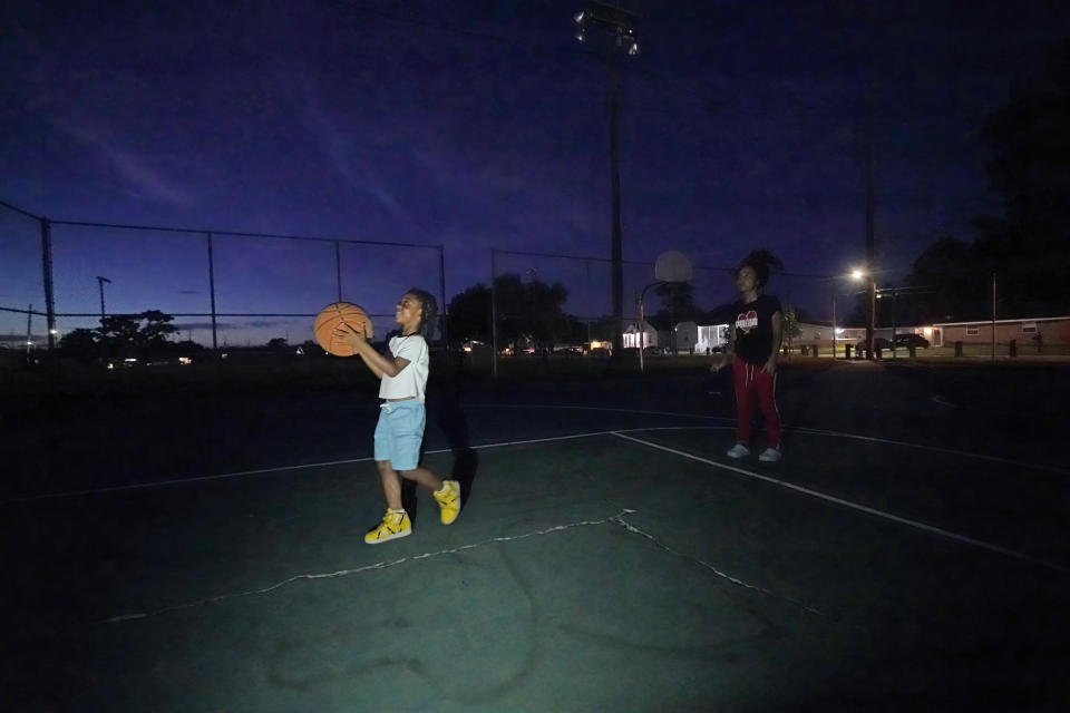 Jada Riley plays on a basketball court with her son 6-year-old son Jayden Harris, Thursday, July 28, 2022, near her former apartment in New Orleans. Two months behind on rent, Riley made the difficult decision last month to leave her apartment rather than risk an eviction judgment on her record. Now, she's living in her car with her 6-year-old son, sometimes spending nights at the apartments of friends or her son's father. (AP Photo/Gerald Herbert)