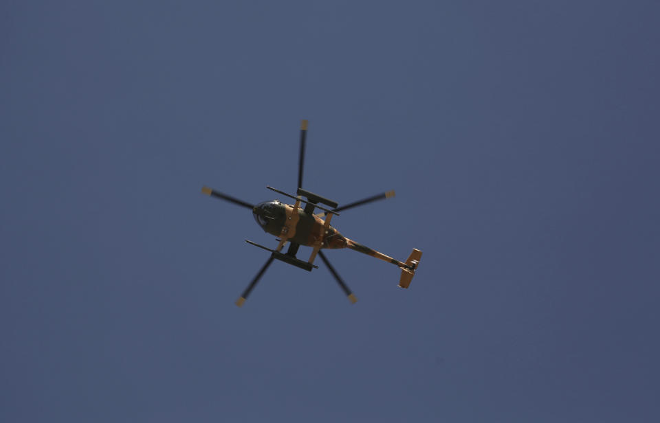 An MD 530F military helicopter hovers to target a house where attackers are hiding in Kabul, Afghanistan, Tuesday, Aug. 21, 2018. The Taliban fired rockets toward the presidential palace in Kabul Tuesday as President Ashraf Ghani was giving his holiday message for the Muslim celebrations of Eid al-Adha, said police official Jan Agha. (AP Photo/Rahmat Gul)