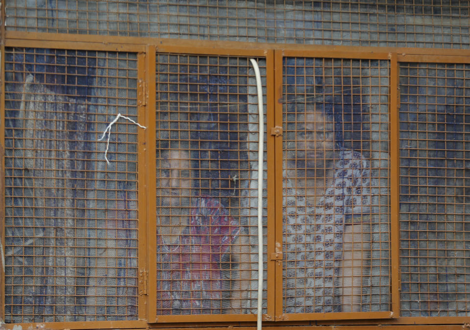 In this Aug. 23, 2019, photo, Kashmiri Hindu women look from inside their residence at the Jagti migrant camp in Jammu, India. Tens of thousands of Kashmiri Hindus fled the restive region nearly 30 years ago, and the ghost of insurgency and their mass exodus still haunts them. They celebrated after India’s Hindu nationalist-led government stripped political autonomy from its part of Muslim-majority Kashmir on Aug. 5. Kashmiri Hindus view it as a step toward justice and possible return to their homeland. But many are still wary of returning. (AP Photo/Channi Anand)