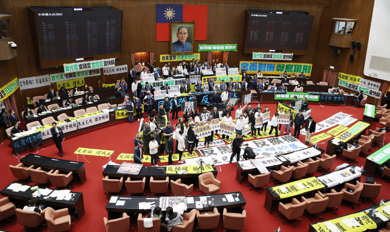 立法院會24日續審國會改革法案，民進黨立委在議場中間高舉看板、呼口號，表達立場。（中央社）