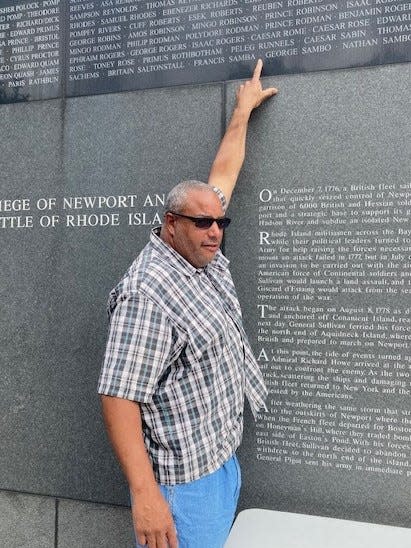 Taunton resident Jason Roomes points to his ancestor's name Ceasar Roomes on a memorial wall in Portsmouth that honors soldiers who fought in the 1st Rhode Island Regiment.