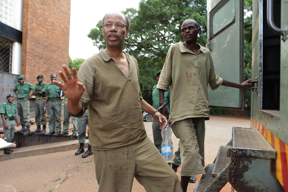 Former US Congressman Mel Reynolds, centre left, prepares to enter a prison truck while handcuffed following his court appearance at the magistrates courts in Harare, Thursday, Feb. 20, 2014. Reynolds was arrested in Zimbabwe for allegedly possessing pornographic material and violating immigration laws. (AP Photo/Tsvangirayi Mukwazhi)